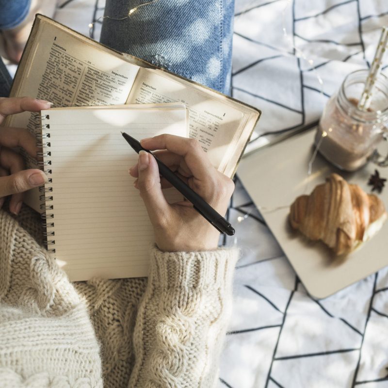 crop-woman-making-notes-near-camera-breakfast-food